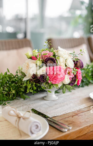 Ordinatamente intrecciati in un tubo sala da pranzo igienico decorate con un rametto di pistacchio. Banchetti per matrimoni o cene di gala. Il tavolo e sedie per gli ospiti, Servita con posateria e stoviglie. party sulla terrazza Foto Stock