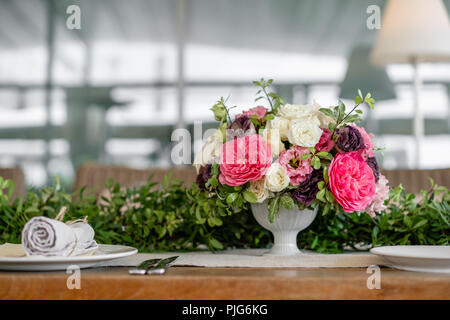 Ordinatamente intrecciati in un tubo sala da pranzo igienico decorate con un rametto di pistacchio. Banchetti per matrimoni o cene di gala. Il tavolo e sedie per gli ospiti, Servita con posateria e stoviglie. party sulla terrazza Foto Stock