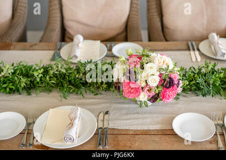 Ordinatamente intrecciati in un tubo sala da pranzo igienico decorate con un rametto di pistacchio. Banchetti per matrimoni o cene di gala. Il tavolo e sedie per gli ospiti, Servita con posateria e stoviglie. party sulla terrazza Foto Stock