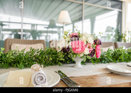 Ordinatamente intrecciati in un tubo sala da pranzo igienico decorate con un rametto di pistacchio. Banchetti per matrimoni o cene di gala. Il tavolo e sedie per gli ospiti, Servita con posateria e stoviglie. party sulla terrazza Foto Stock