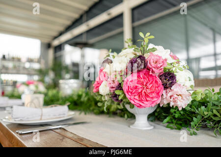 Ordinatamente intrecciati in un tubo sala da pranzo igienico decorate con un rametto di pistacchio. Banchetti per matrimoni o cene di gala. Il tavolo e sedie per gli ospiti, Servita con posateria e stoviglie. party sulla terrazza Foto Stock