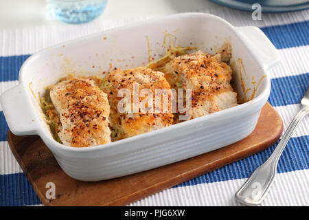 Cotto al forno MERLUZZO IMPANATO pesce su letto di verdure Foto Stock