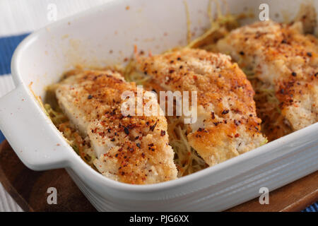 Cotto al forno MERLUZZO IMPANATO pesce su letto di verdure Foto Stock