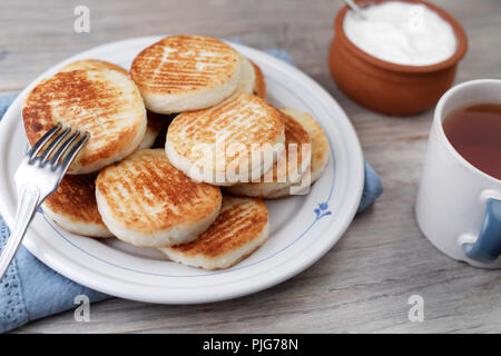 Syrniki, il tradizionale formaggio russo frittelle su un tavolo rustico Foto Stock