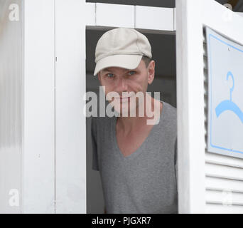 L uomo esce dalla modifica di stallo in una spiaggia Foto Stock