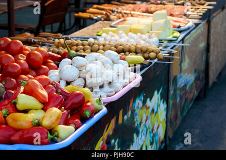 Cucina di strada e cucina outdoor concept. Verdure, carni, formaggi, funghi, pesce su spiedini per friggere su un fuoco aperto. Foto Stock