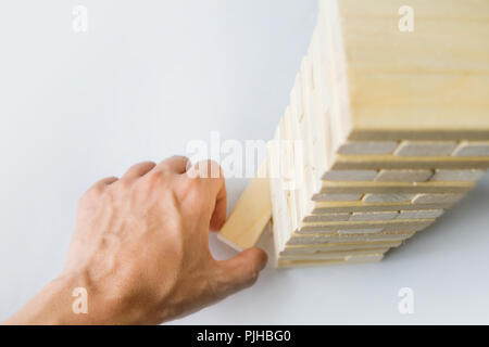 La torre da blocchi di legno e di mano d'uomo prendere un blocco. Il gioco dei dadi su un tavolo bianco. La vista dall'alto Foto Stock