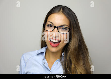 Bella Donna sorridente in occhiali guardando la telecamera su sfondo grigio. Close up felice giovane donna indossa occhiali che mostra il sorriso toothy Foto Stock