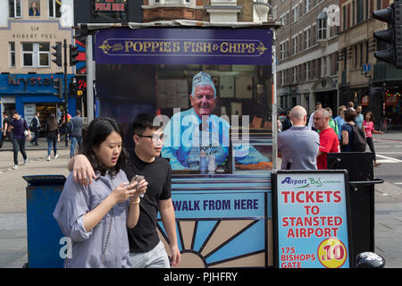 Un asiatico giovane a piedi passato la parte posteriore di un giornale del fornitore esterno kiosk Liverpool Street Mainline station nella città di Londra - la capitale del distretto finanziario, il 3 settembre 2018, a Londra Inghilterra. Foto Stock