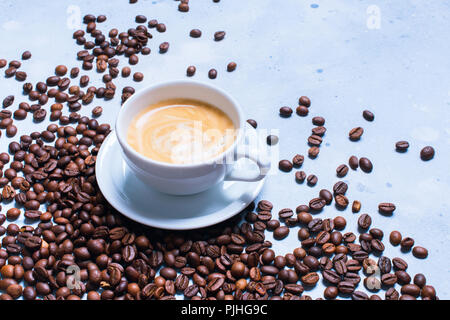 White tazza di caffè fresco sparsi grani di cibo malsano sfondo blu Foto Stock