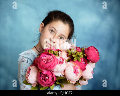 Poco carino ragazza con un mazzo di fiori in studio Foto Stock