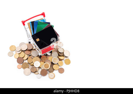 Carrello della spesa con carte di credito è in sella a una pila di monete su sfondo bianco. Le carte di credito sono vincenti e la liquidità di cassa è sconfitto. Vecchio e nuovo pagamento m Foto Stock