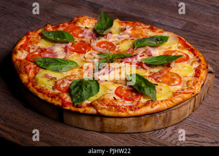 Pizza con prosciutto e patate servita il basilico Foto Stock