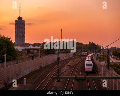 Tramonto a Augsburg con la stazione ferroviaria e la torre e treni Foto Stock