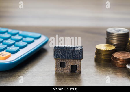 Modello di casa, la pila di monete e calcolatrice. Concetto Casa in vendita, dell'acquisto, prestito e finanza aziendale. Foto Stock