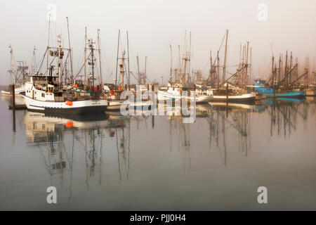 Nebbia di mattina inizia a sollevare rivelando dell'Oregon Yaquina Bay flotta da pesca a Newport. Foto Stock