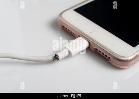 Chiudere l immagine del danneggiato charger cavo di collegamento con lo smartphone su sfondo grigio Foto Stock