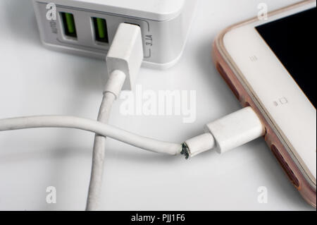 Chiudere l immagine del danneggiato charger cavo di collegamento con lo smartphone su sfondo grigio Foto Stock