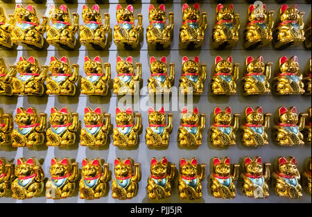 Una parete con molti fortunati gatti Maneki-Neko vista frontale. Foto Stock