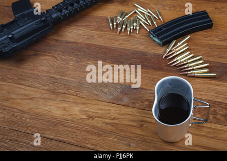 Fucile da assalto e la tazza di caffè sul tavolo in legno sfondo Foto Stock