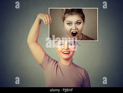 Giovane donna sorridente tenendo fermo immagine di se stessa in stato d'animo arrabbiato e urlando avente personalità scissa Foto Stock