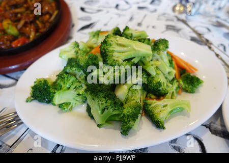 Friggere i broccoli e la carota sulla piastra bianca