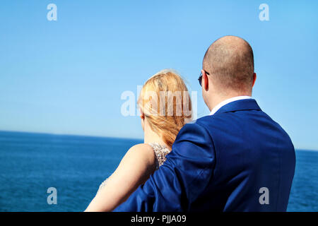 Nozze. Coppia felice giorno dopo il matrimonio. Bella giovane accogliere a braccia aperte guardando il mare in lontananza. Coppie in viaggio di nozze in soggiorno nel mare. Foto Stock