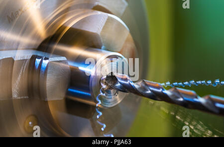 La foratura su tornio close-up. Trucioli metallici. Pezzo metallico serrato in una macchina a rotazione mandrino. Punte trapano in acciaio bit. Twisted swarfes. Sfondo verde. Foto Stock