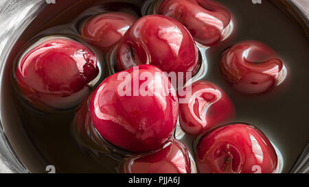 Ciliegie dolci nel proprio succo di close-up. Bella dettaglio di colore rosso ciliegia conserve di frutti di bosco in un lucido sciroppo. Deliziosa fruttato sano dessert vegetariano. Foto Stock