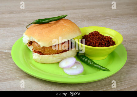 Vada Pav con fette di cipolla peperoncino verde e chutney di aglio, una rinomata cucina di strada in India Foto Stock