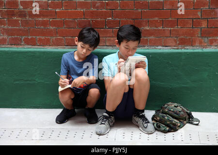 2 ragazzi stanno facendo la loro homeworks su strada Foto Stock