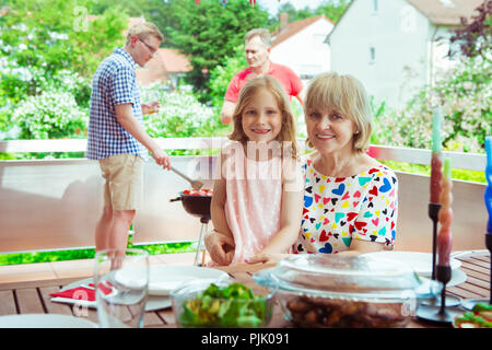 Felice famiglia grande divertimento e godetevi il loro parlare con figli e nipoti durante la grigliatura a terrasse Foto Stock