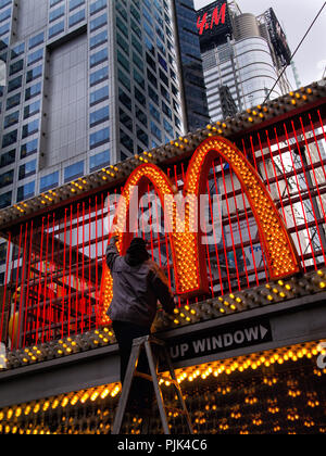 Un uomo cambiare le lampadine della luce su un Mc Donald's annuncio a Manhattan, New York City, Stati Uniti d'America Foto Stock