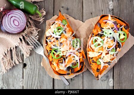 Patate dolci al forno farcito con pollo e verdure e formaggio, sopra visualizza su un rustico sfondo legno Foto Stock