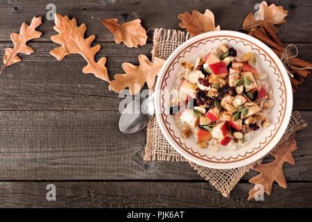 In autunno i fiocchi d'avena con mele, Cranberries, semi e noci, vista dall'alto in legno con foglie di autunno Foto Stock