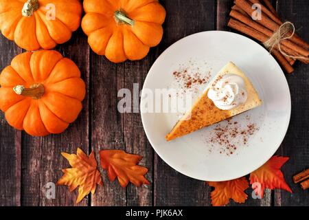 Fetta di zucca cheesecake con panna montata, vista dall'alto su un rustico sfondo di legno Foto Stock