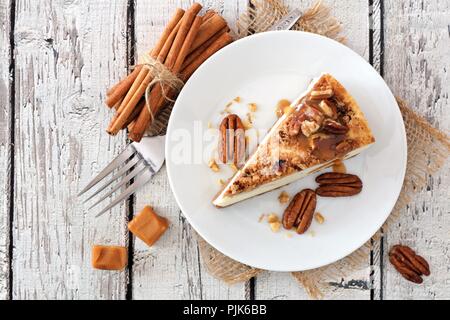 Fetta di noci pecan cheesecake al caramello, vista dall'alto su un rustico di legno bianco sullo sfondo Foto Stock
