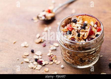 Muesli, muesli in un barattolo di vetro. Una sana prima colazione. Organici di avena con mele bacche e dadi. Copia dello spazio. Foto Stock