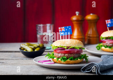 Burger con bandiera australiana sulla parte superiore. Sfondo di legno Foto Stock