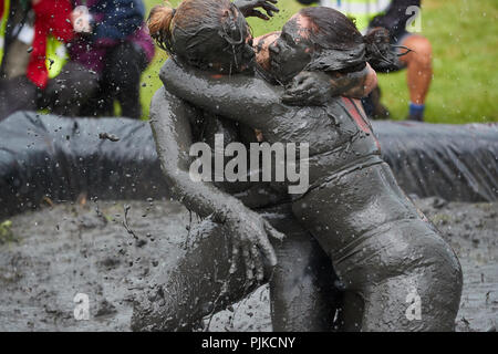 Due donne fango wrestling con in pianura giochi, Thorney, Somerset, Inghilterra Foto Stock