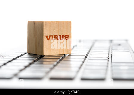 Close up concettuale cubo di legno con virus testo sul lato superiore del computer portatile tastiera, isolati su sfondo bianco. Foto Stock