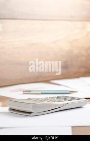 In plastica bianca calcolatrice desk su un documento stampato, documenti di lavoro o di assegnazione, su una scrivania di legno o spazio di lavoro di close-up. Adatto per viaggi di affari, accou Foto Stock