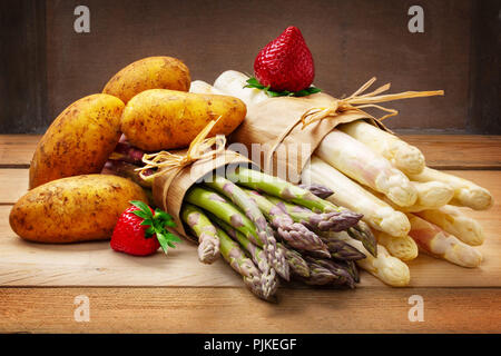 Asparagi, fragole e patate su legno Foto Stock