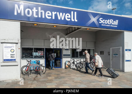 I passeggeri che provengono Motherwell ScotRail stazione ferroviaria. Due uomini con zaini, una donna tirando una valigia su ruote. Rastrelliere per biciclette. Nord Lanarksh Foto Stock