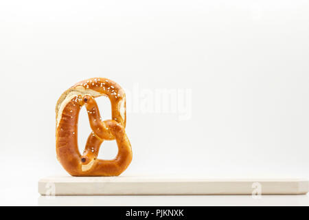 Un pretzel, posto su una tavola di legno contro uno sfondo luminoso, la lettera "B" come la Baviera o Brezn, Foto Stock