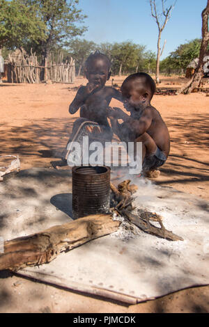Due Himba ragazzi giocare dal fuoco in un villaggio Himba della Namibia Foto Stock