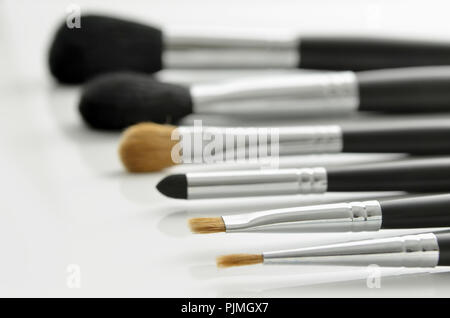 Professional pennelli per il trucco giacente su sfondo bianco. Focus su una spazzola. Foto Stock