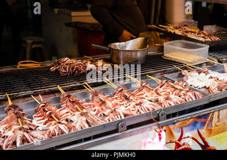 Spiedino di calamari stallo con la cottura di calamari a jie Dihua street market in Taipei Taiwan Foto Stock