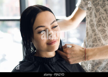 Irriconoscibile parrucchiere creazione di acconciatura per la bella bruna donna Foto Stock