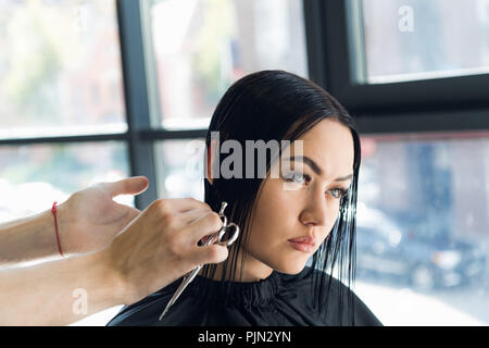 Parrucchiere il taglio di capelli di una bella bruna gravi donna Foto Stock